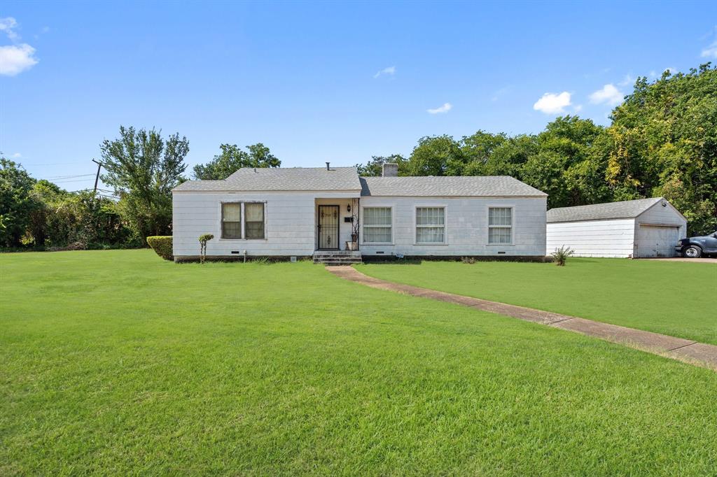 a front view of house with yard and trees in the background