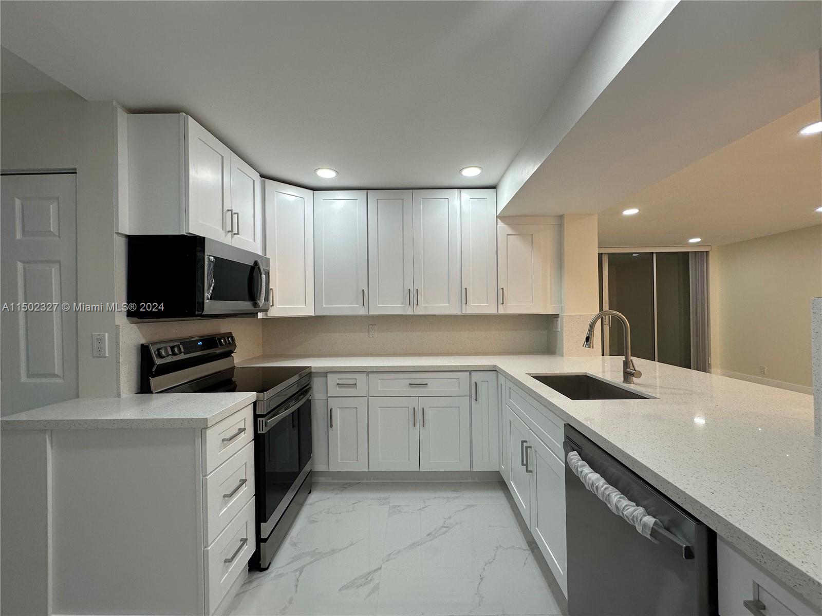 a kitchen with a sink white cabinets and stainless steel appliances