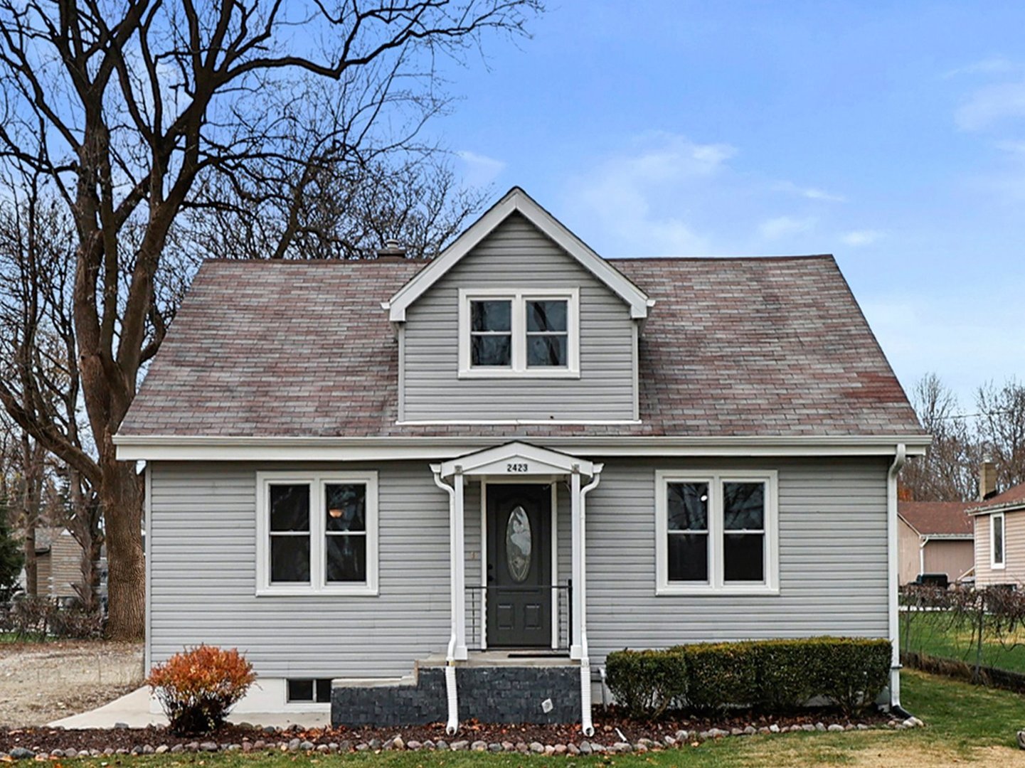 a front view of a house with plants and trees