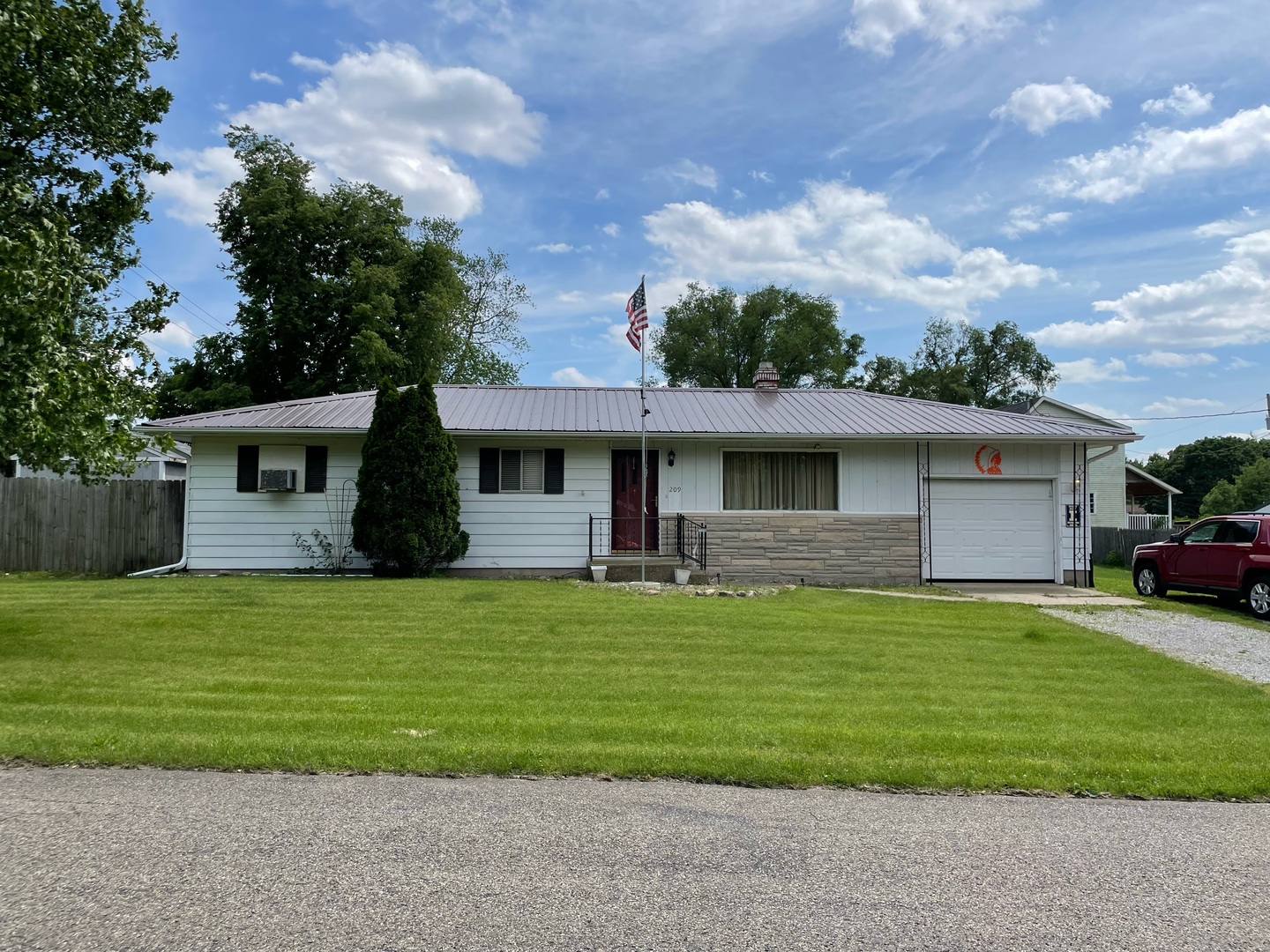 a front view of a house with a garden and trees