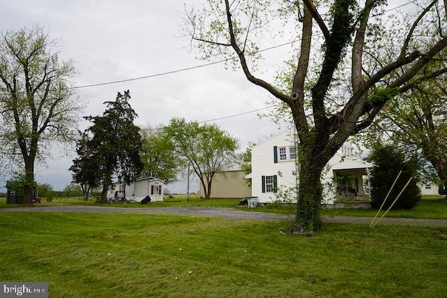 a view of a white house in a big yard with large trees