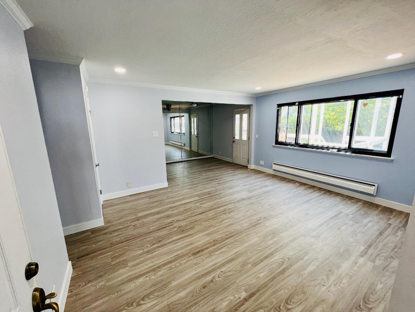 an empty room with wooden floor and windows