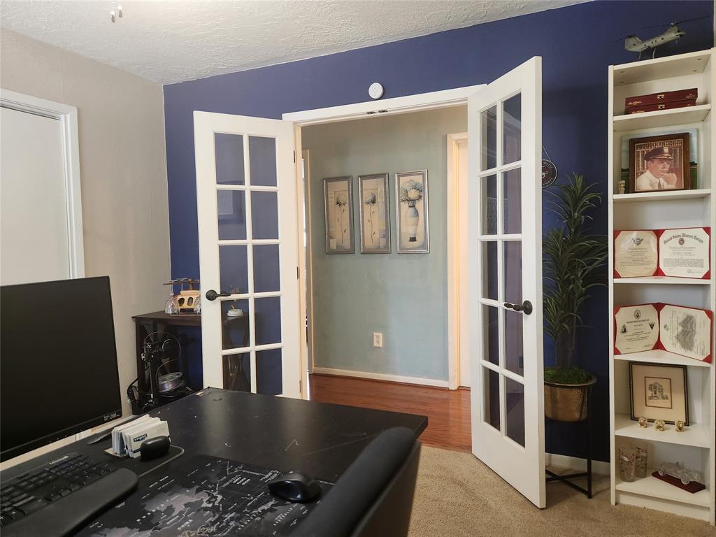 This is an office space with French doors, built-in shelves, and a bold blue accent wall, creating a distinguished work environment within the home.