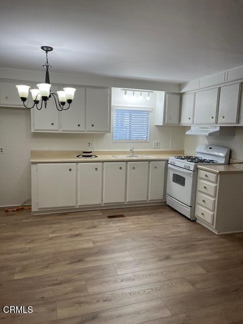 a kitchen with stainless steel appliances granite countertop a stove a sink and white cabinets