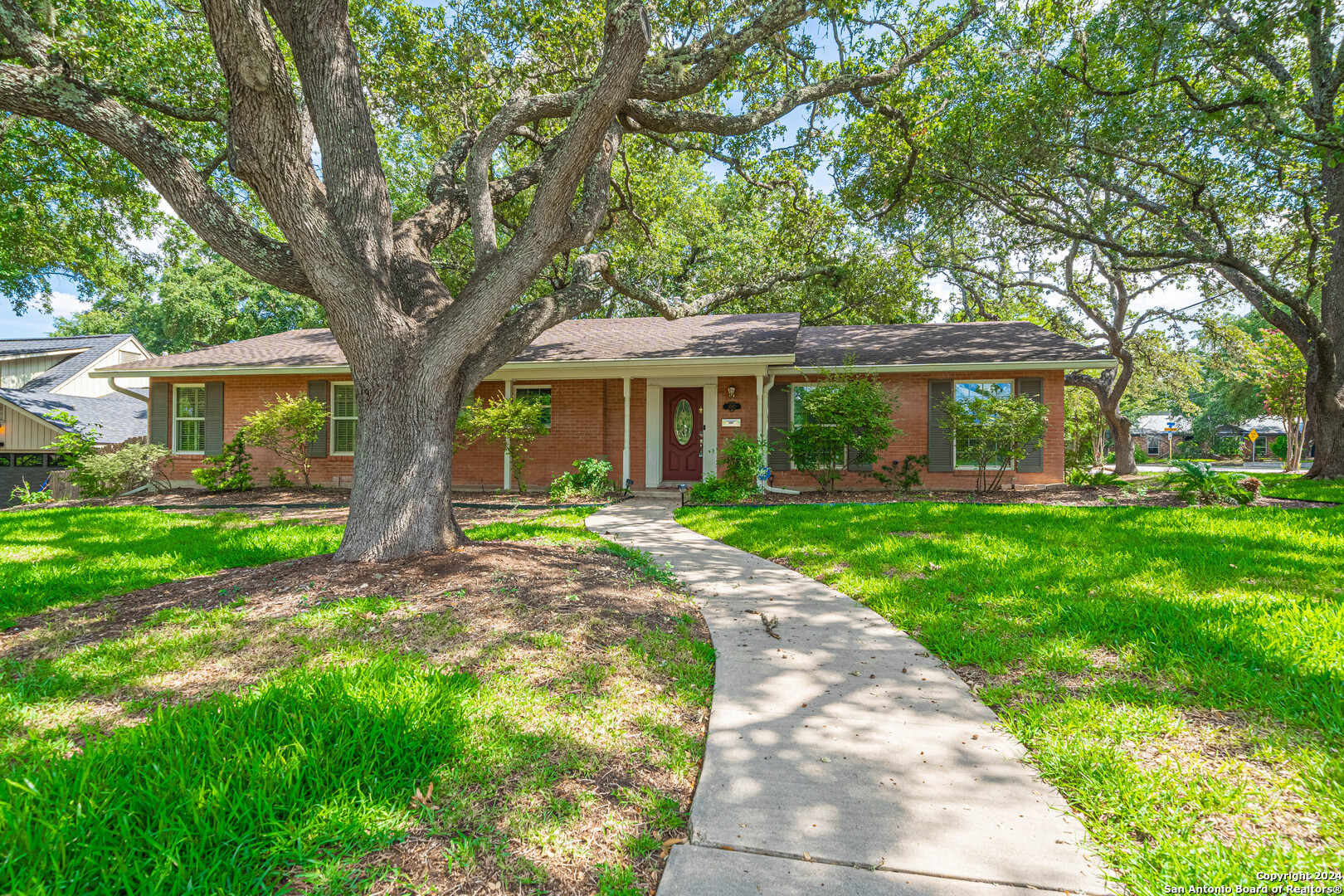 a view of house with a big yard and large trees