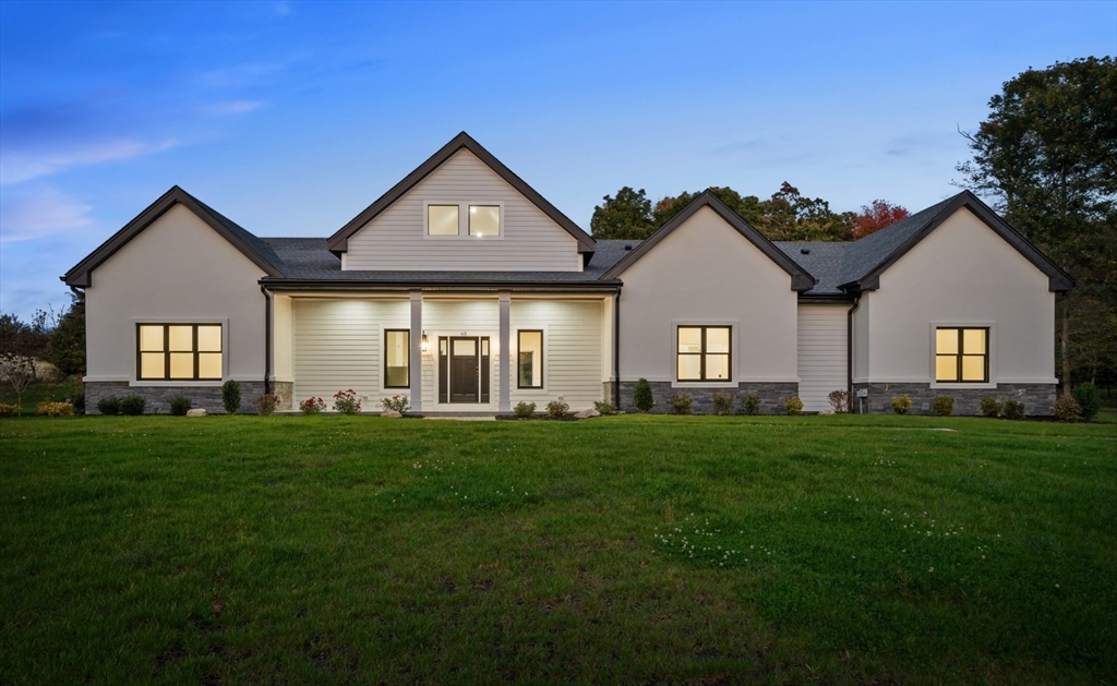 a view of a big yard in front of a house with large windows