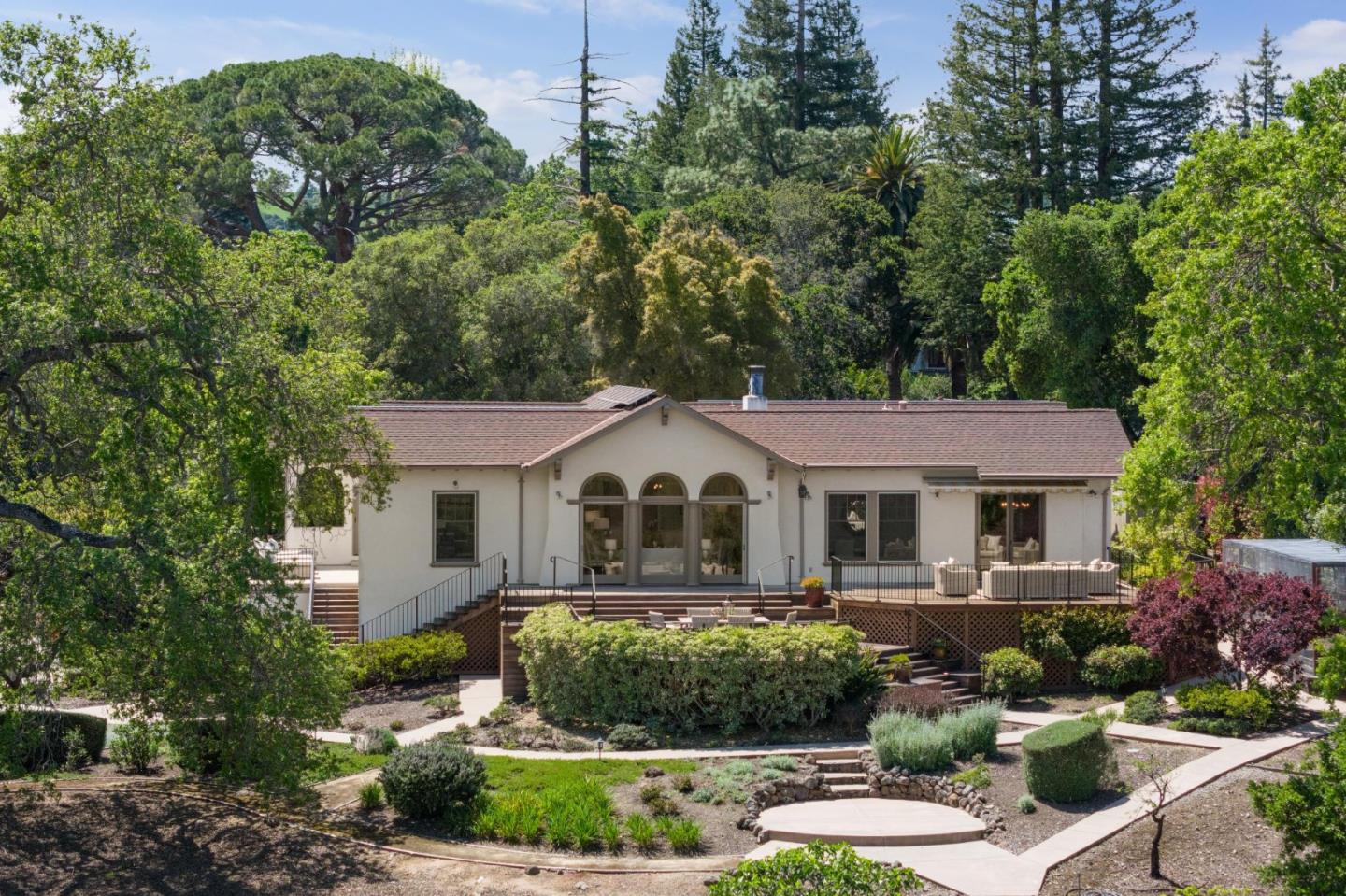 a front view of a house with a yard and large trees