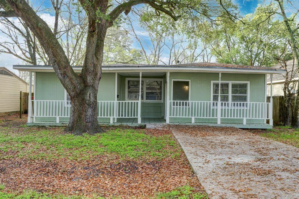 a view of a house with a small yard and large trees