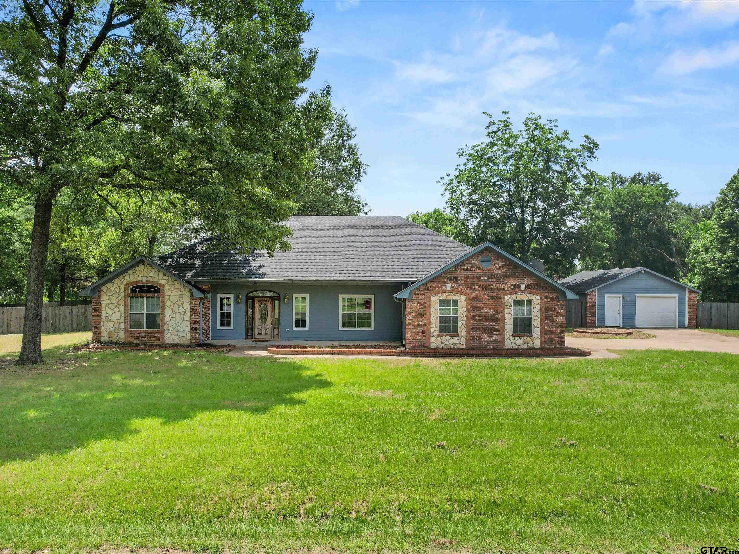 a front view of a house with a yard and trees