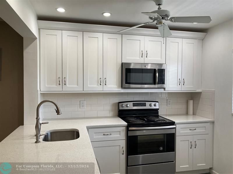 a kitchen with granite countertop white cabinets and stainless steel appliances