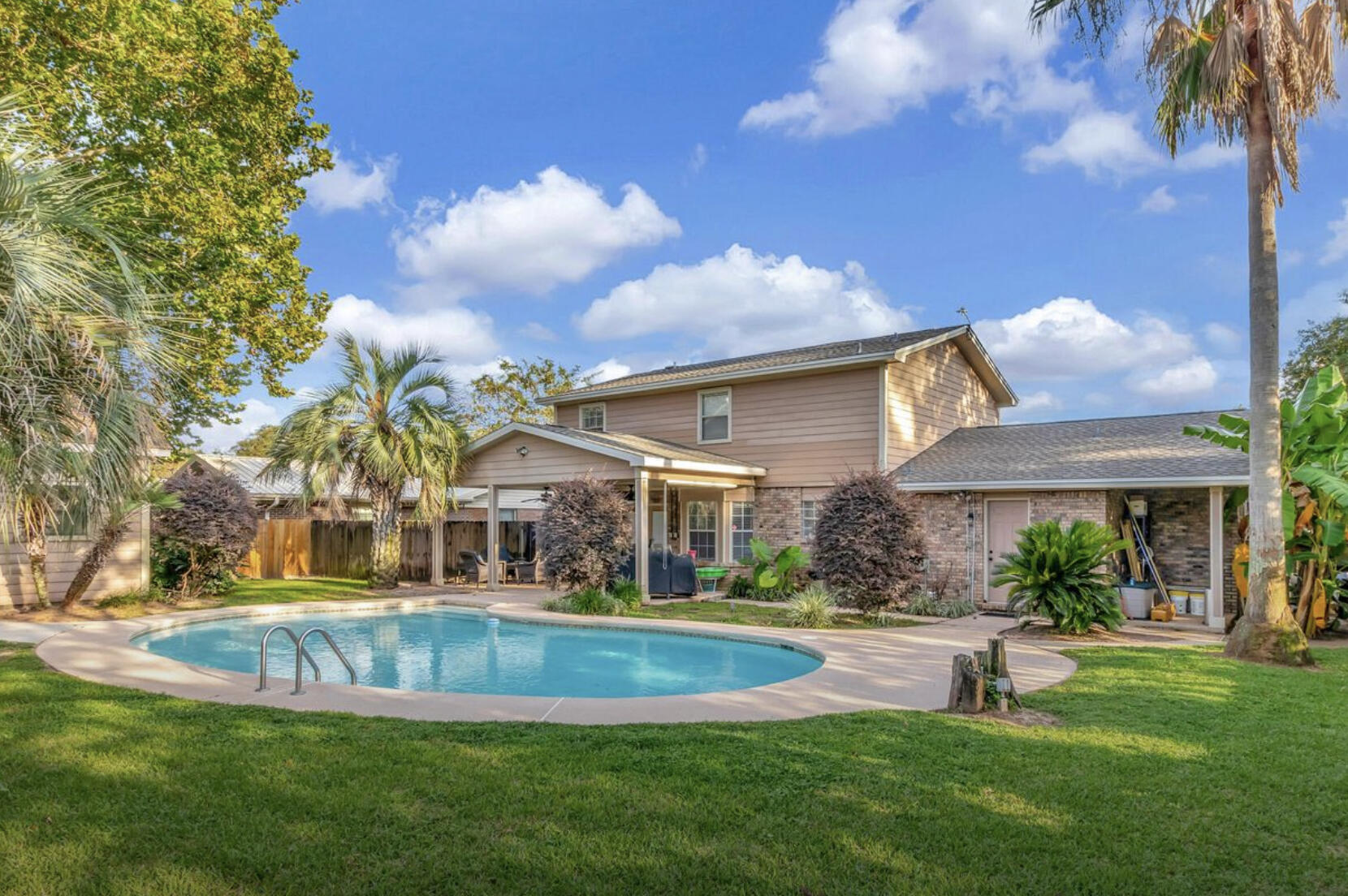 a view of house with a big yard and palm trees