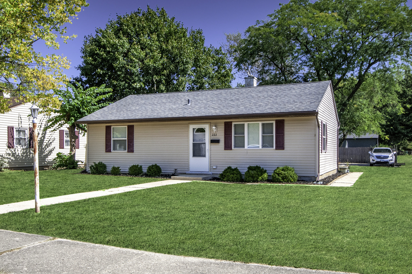 a front view of a house with a garden and trees