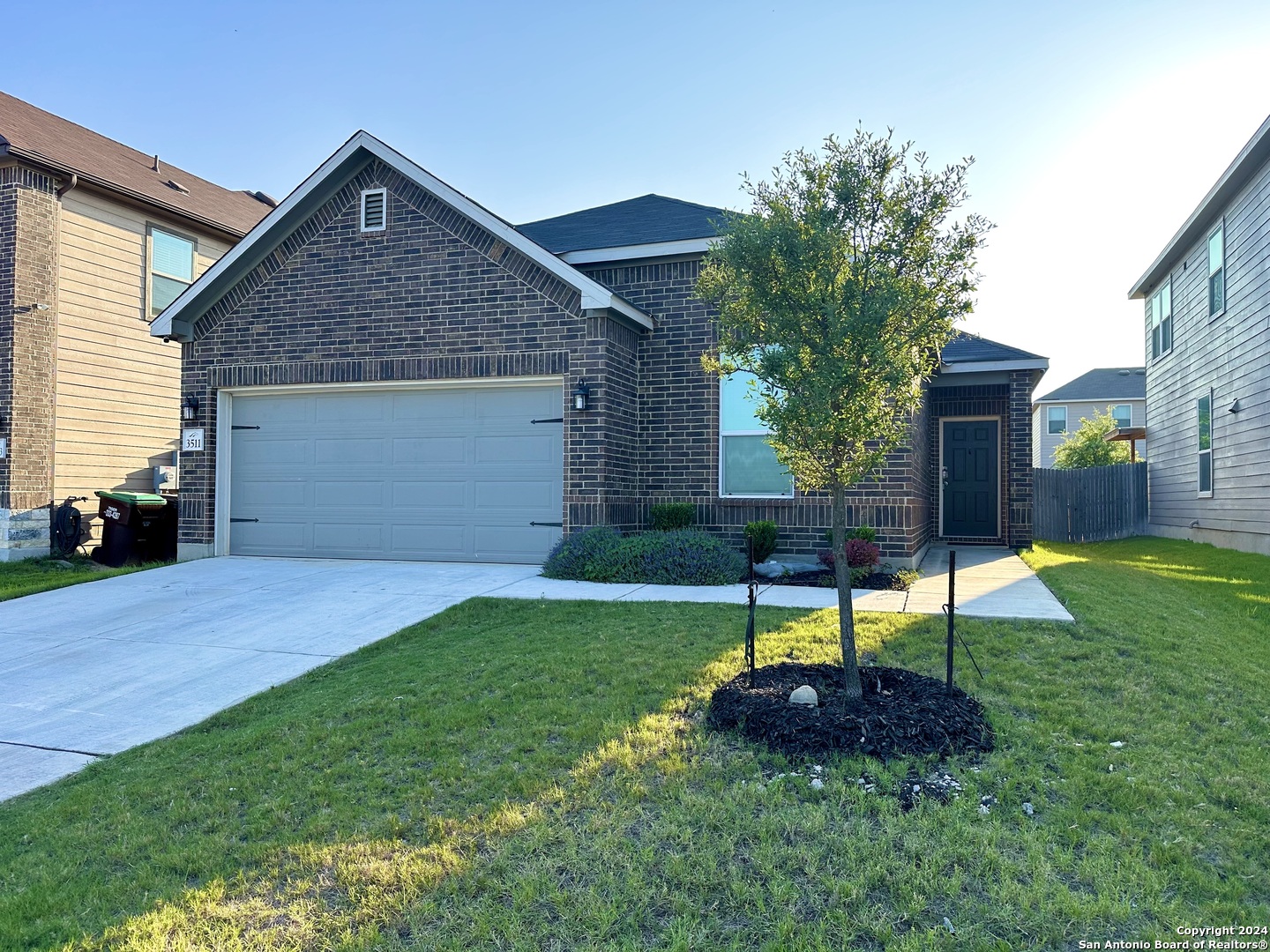 a front view of a house with a yard and a tree