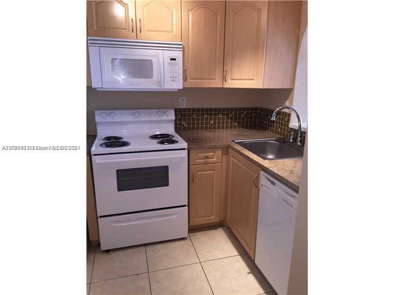 a kitchen with granite countertop white cabinets and white appliances