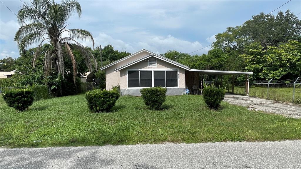 a view of a house with a yard potted plants and a large tree