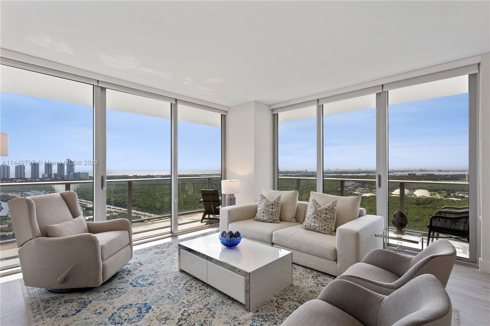 a living room with furniture and floor to ceiling windows