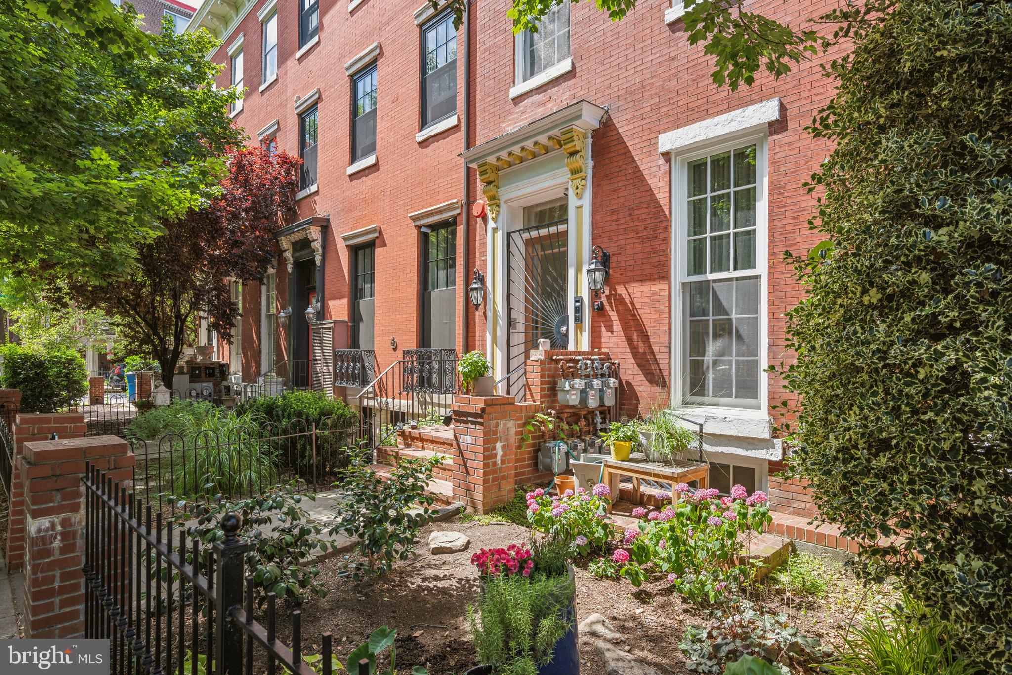 front view of a brick house with a flower plants