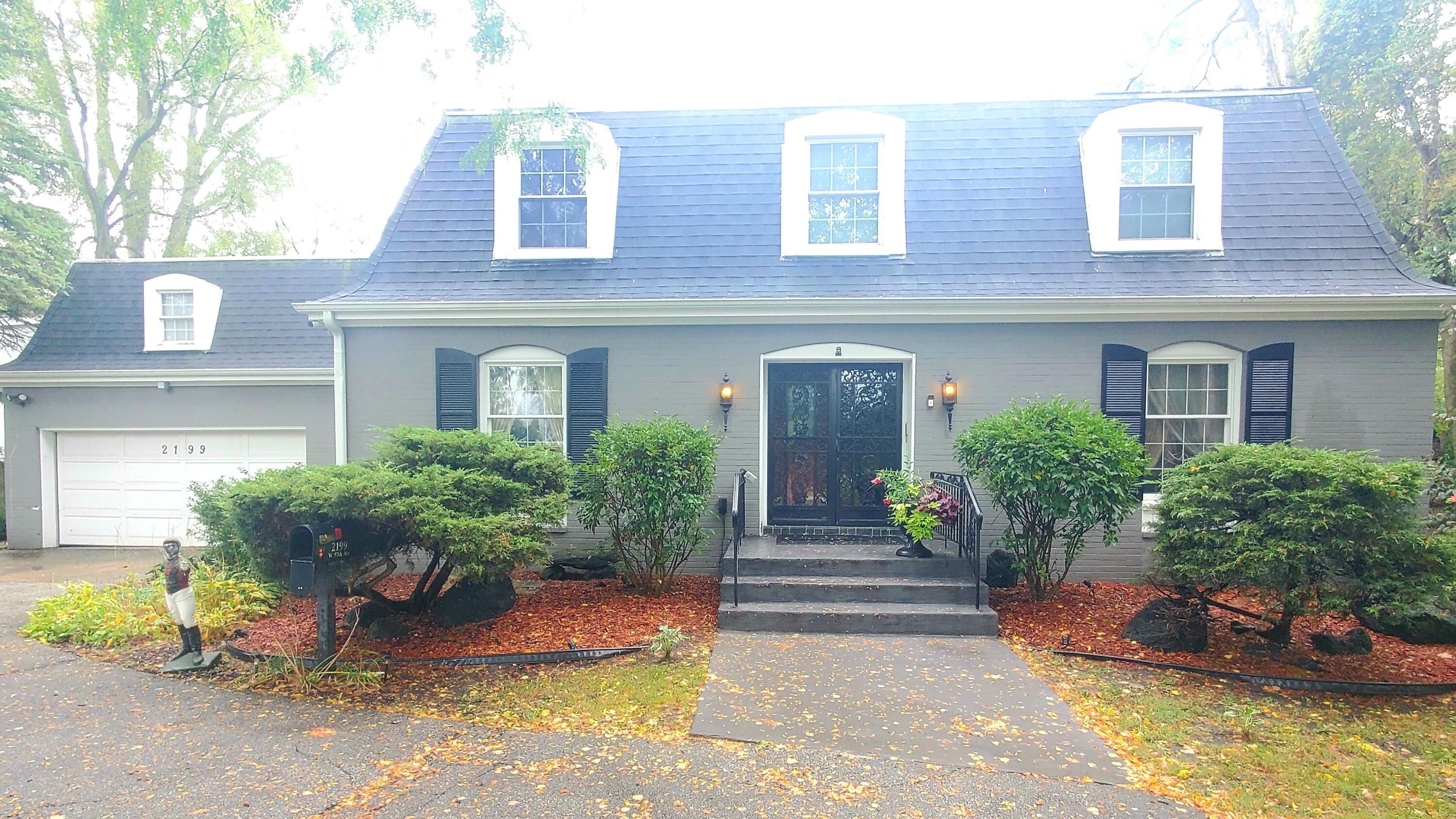 a view of a brick house with potted plants and a bench