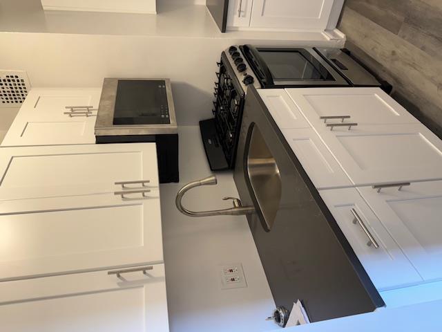 a kitchen with granite countertop white cabinets and black appliances