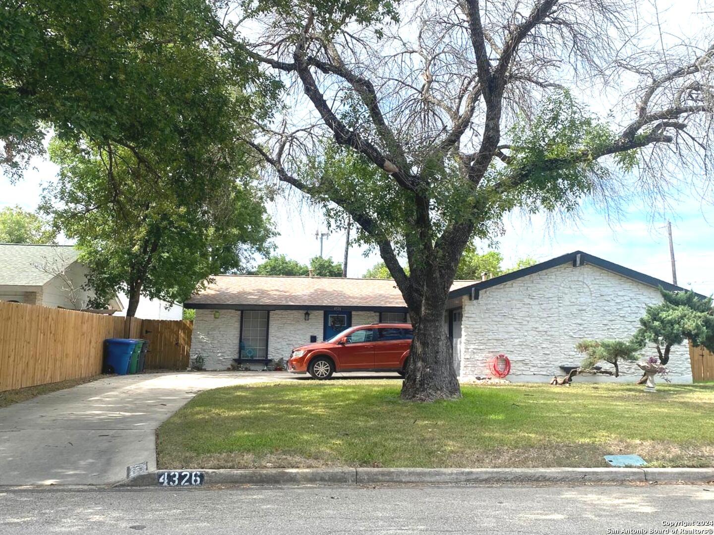 a front view of a house with a garden and trees