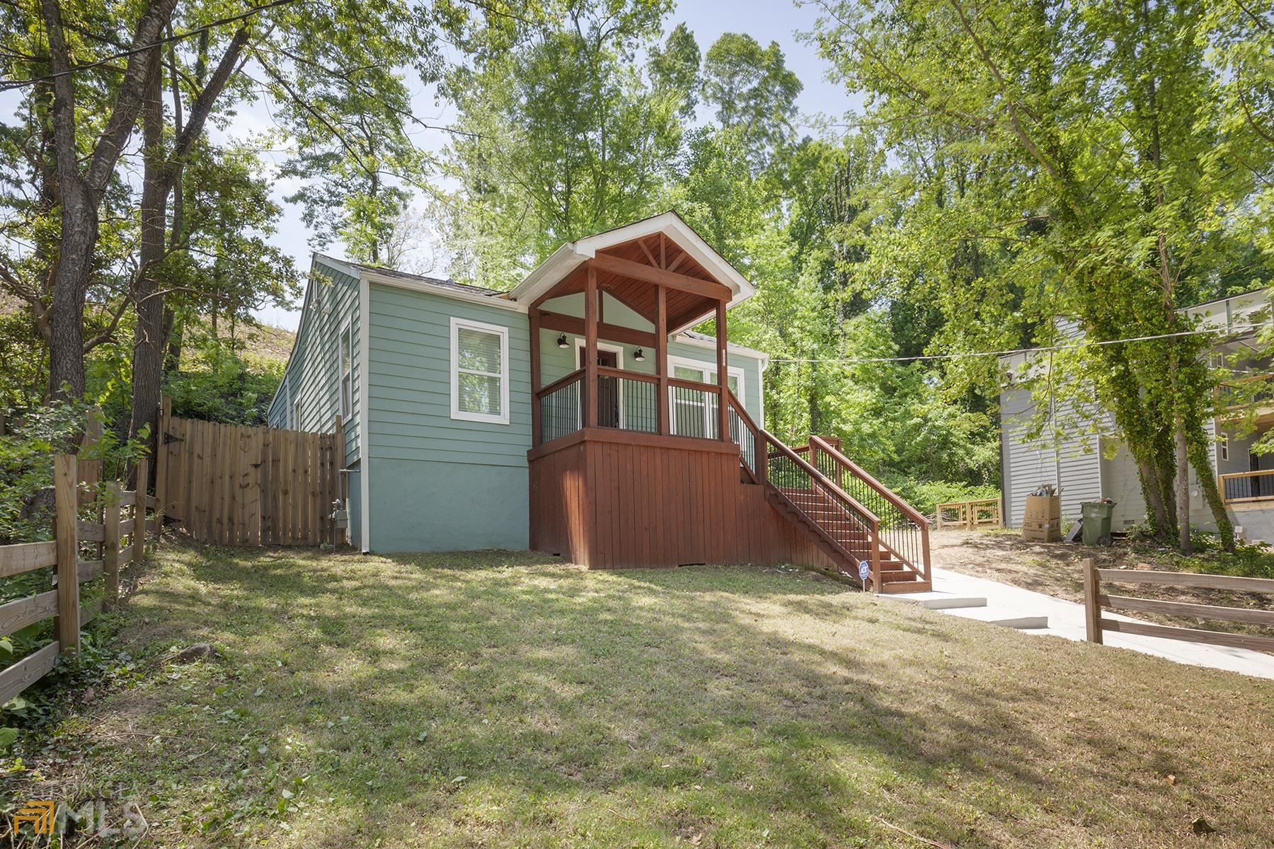 a backyard of a house with wooden fence and large trees