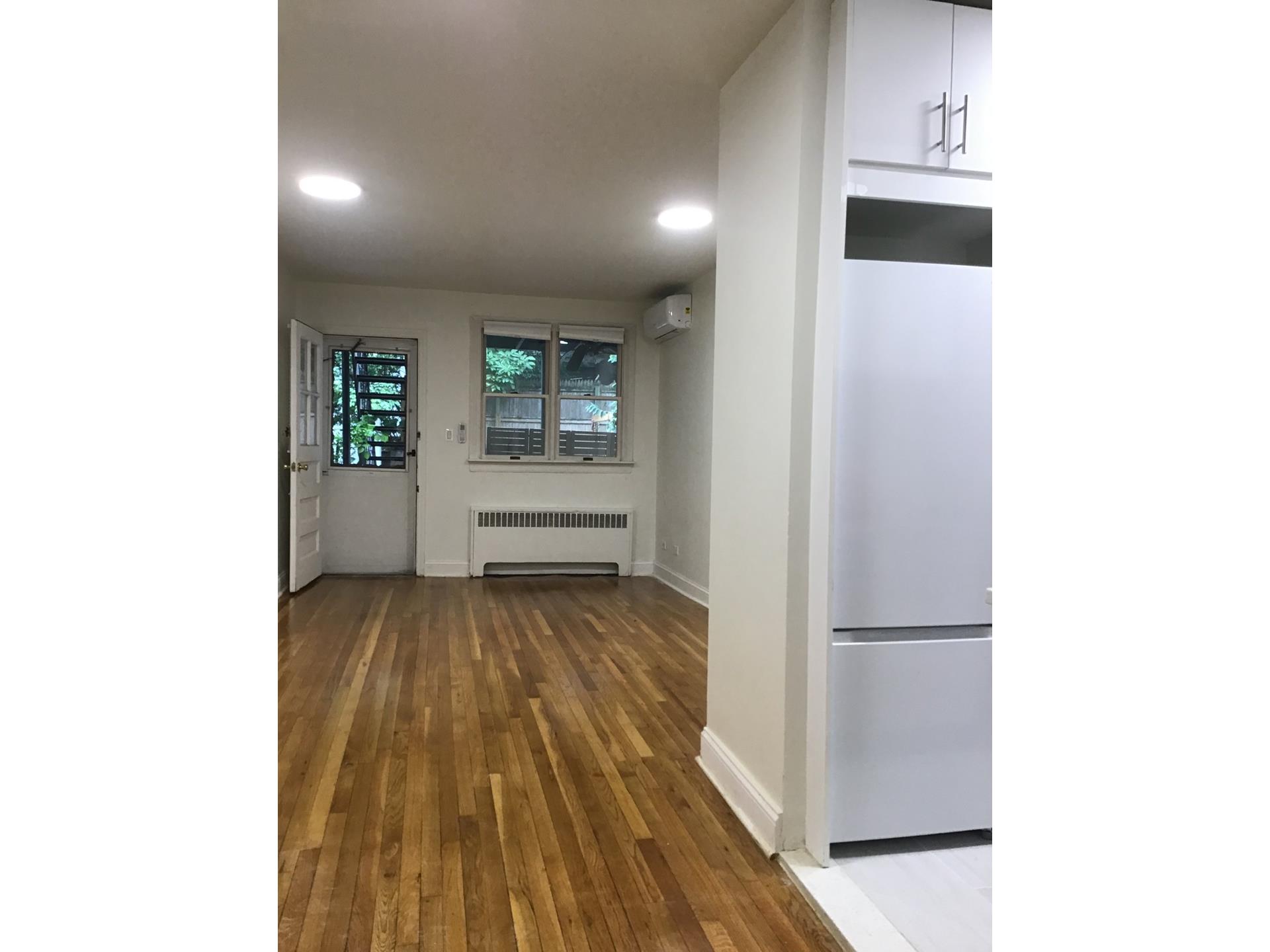 a view of a hallway with wooden floor and a bathroom