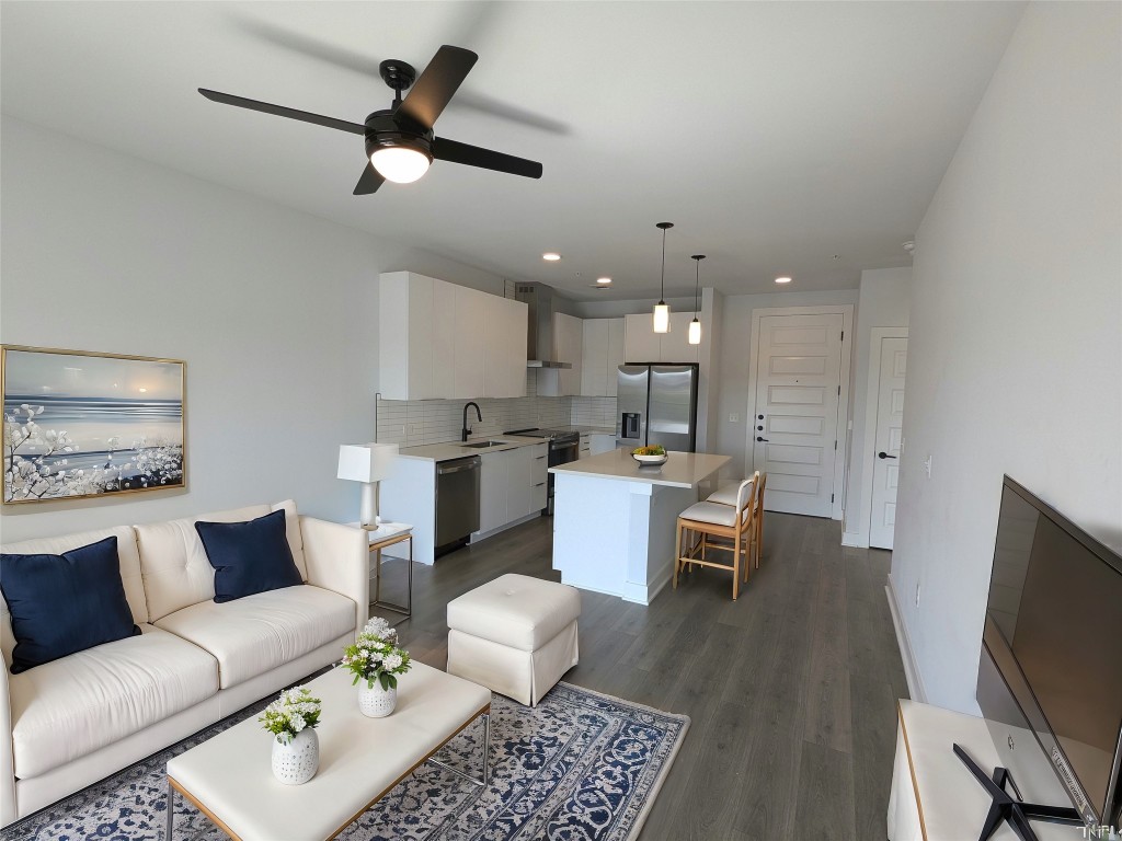 a living room with furniture kitchen view and a flat screen tv