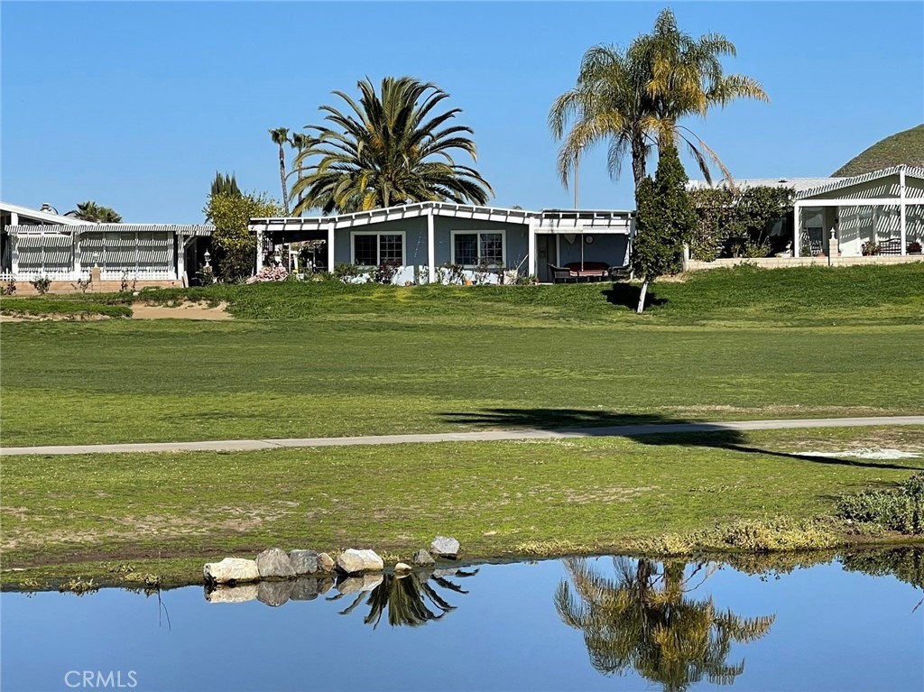 a front view of a house with a garden and lake view