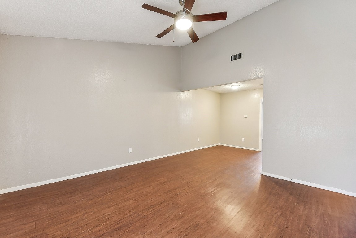 an empty room with wooden floor and fan