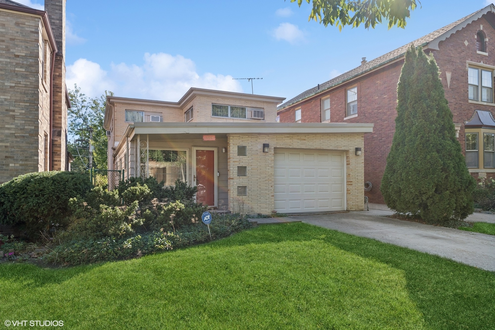 a view of a house with brick walls and a yard with plants