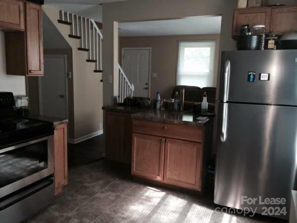 a kitchen with stainless steel appliances granite countertop a refrigerator a stove and a sink