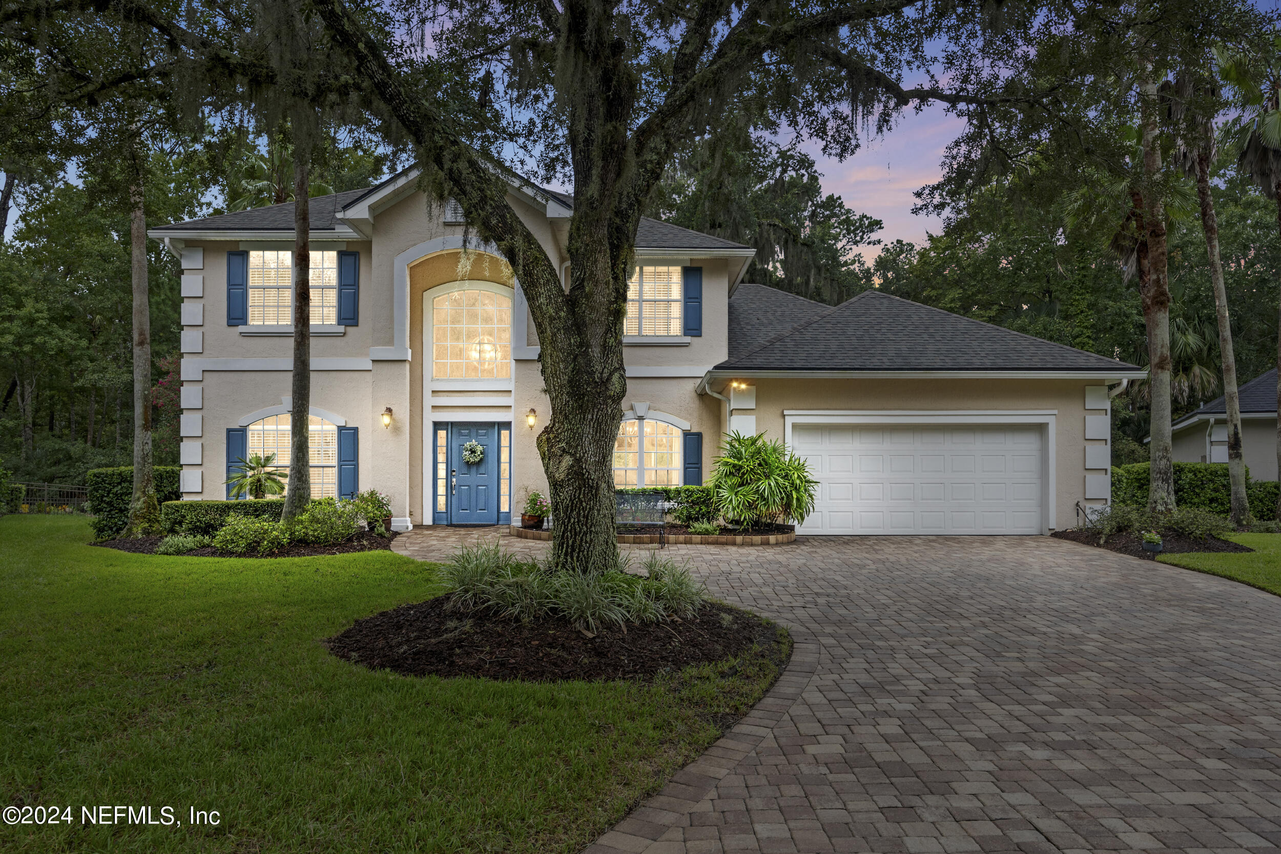 a front view of a house with a garden and trees