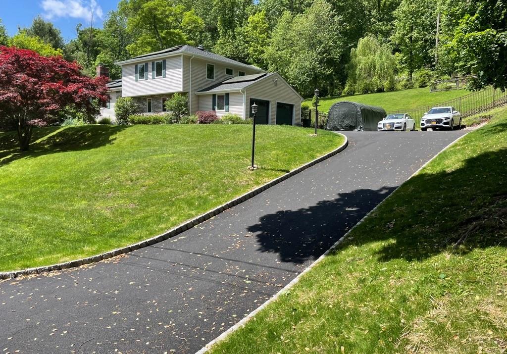 View of front of home with an outdoor structure, a garage, and a front lawn