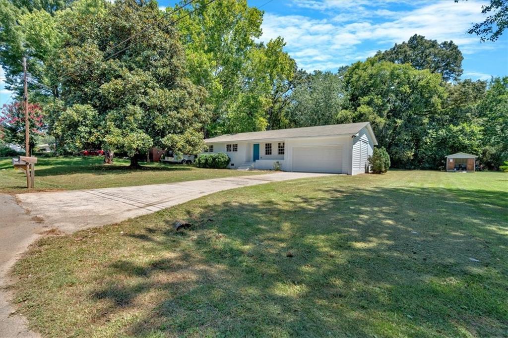 a view of a house with a yard and large trees