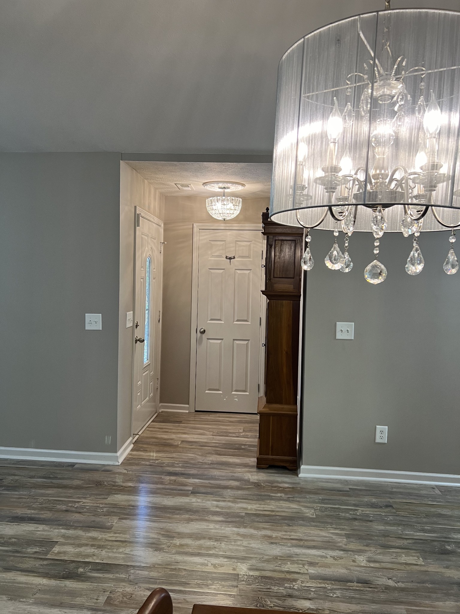 This view showcases the new lighting, updated flooring in the dining area with the front foyer in the background