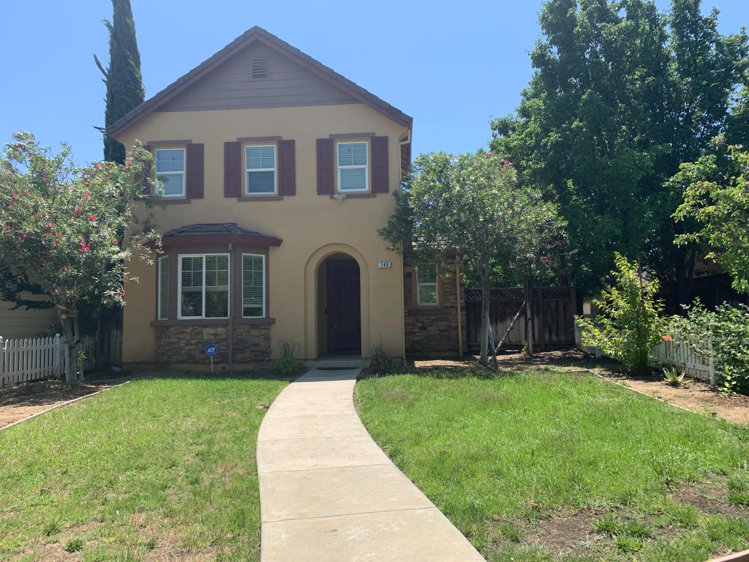 a front view of a house with a yard and trees