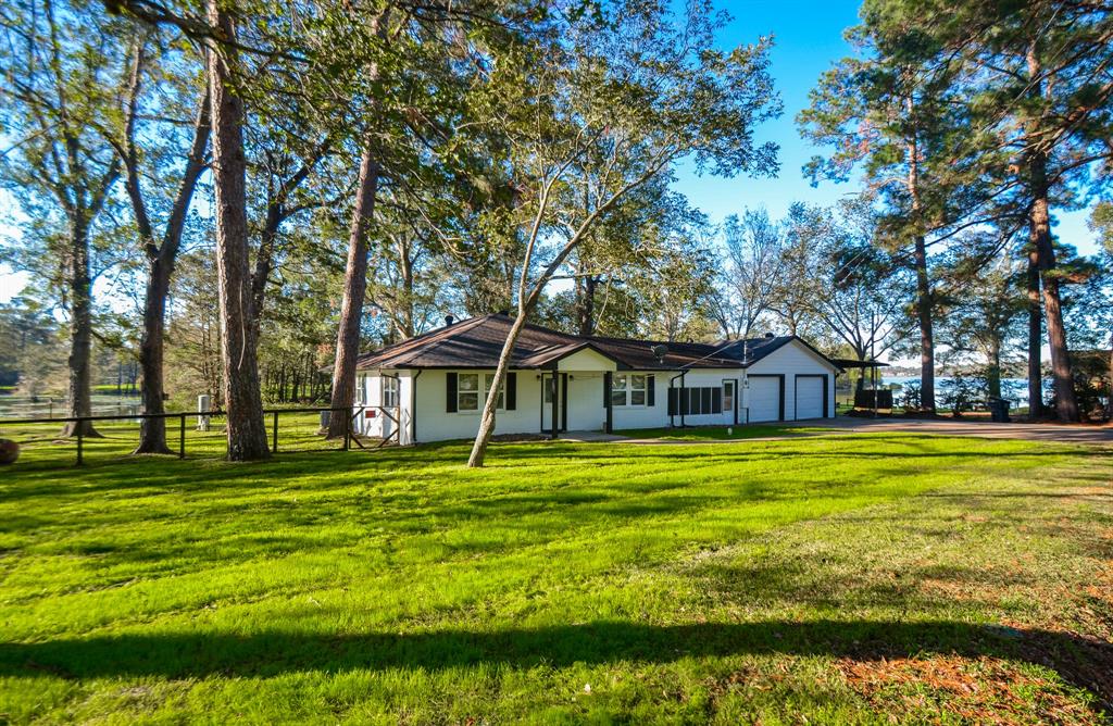 a white house with a big yard and large trees