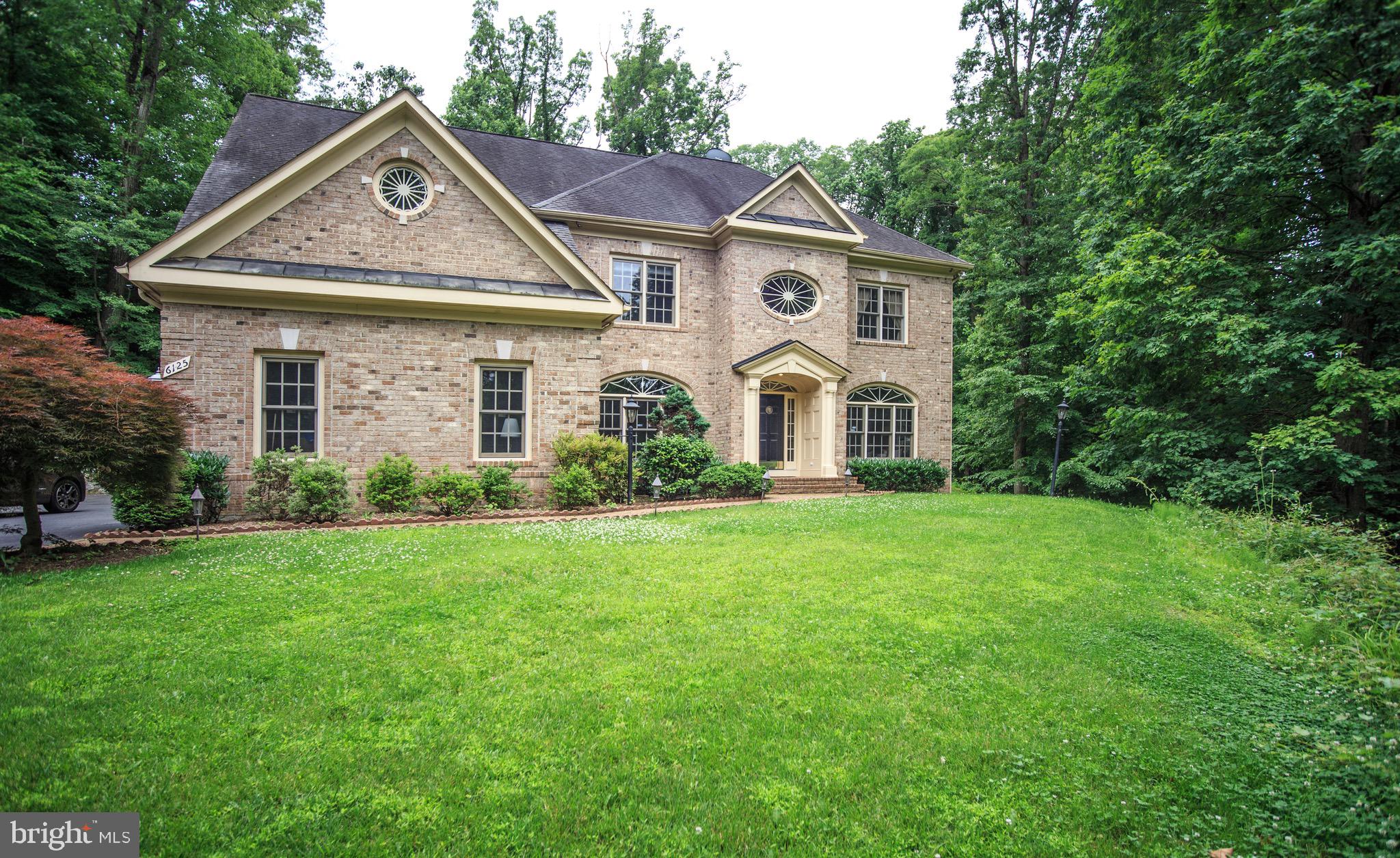 a view of a white house with a big yard and large trees