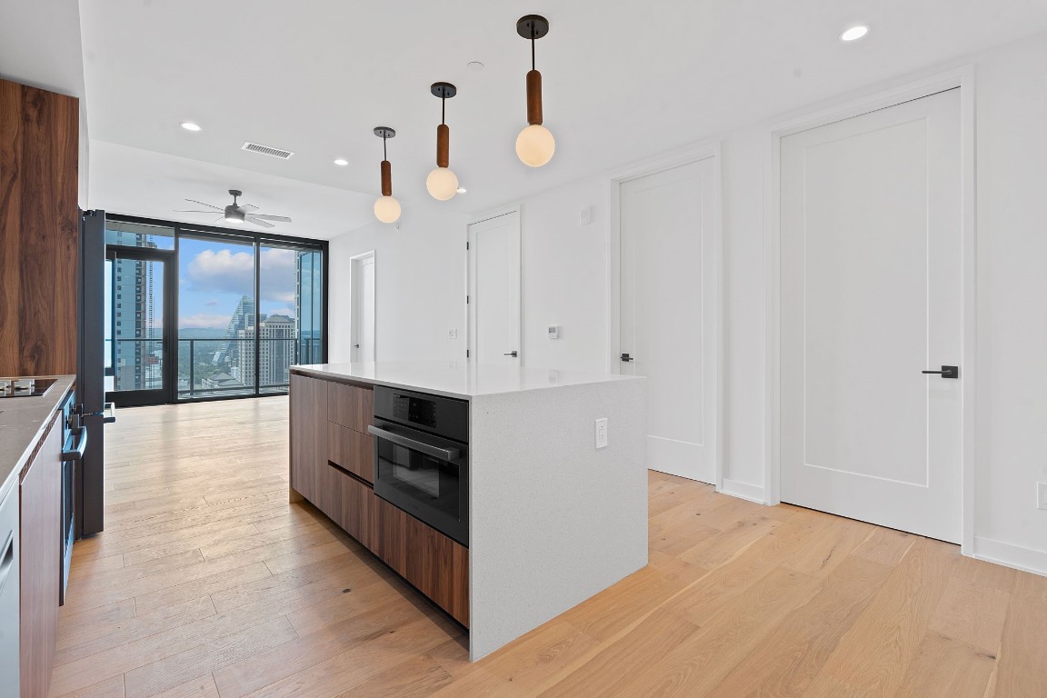 an empty room with wooden floor and kitchen view