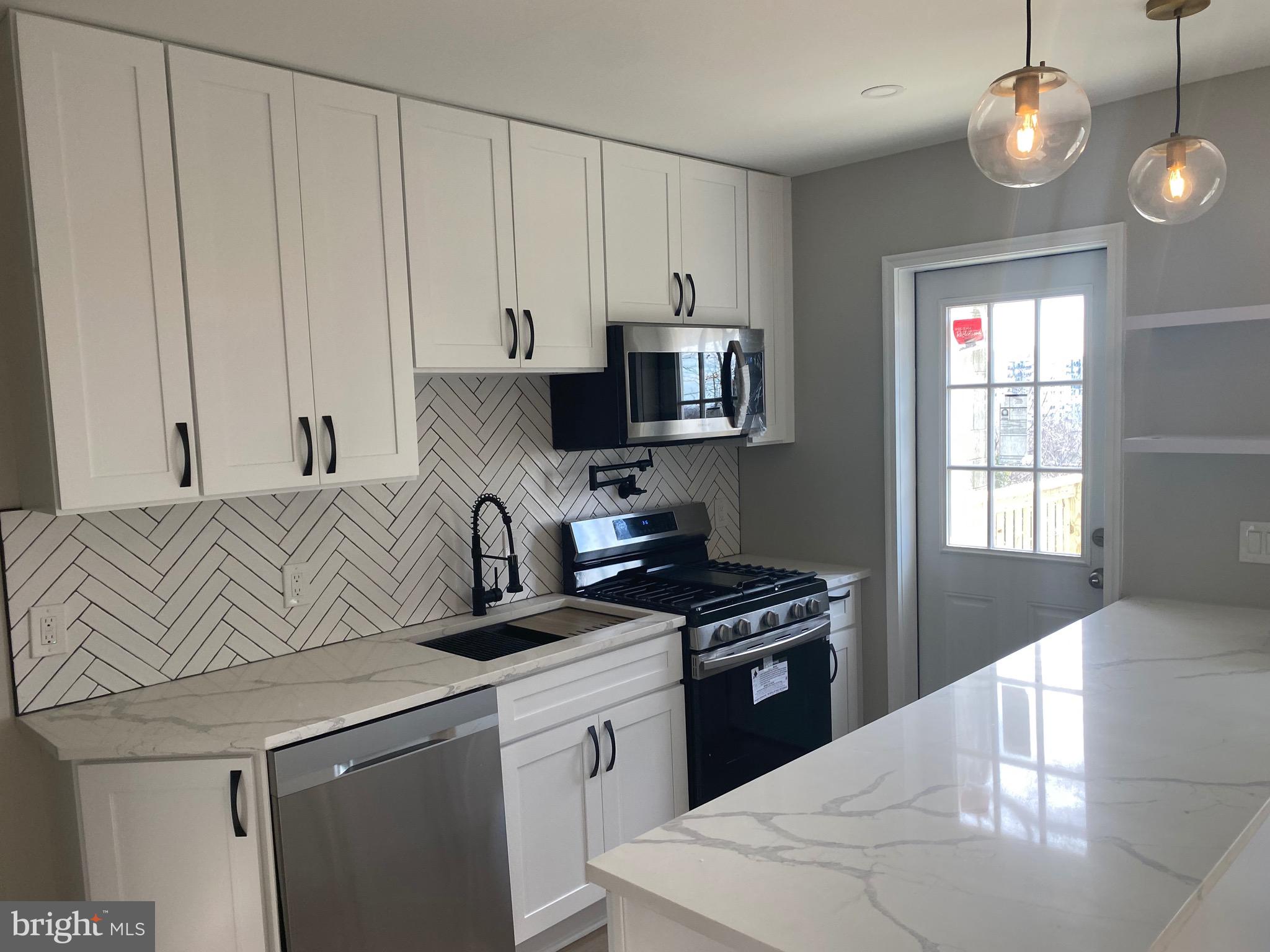 a kitchen with granite countertop a sink a stove and cabinets