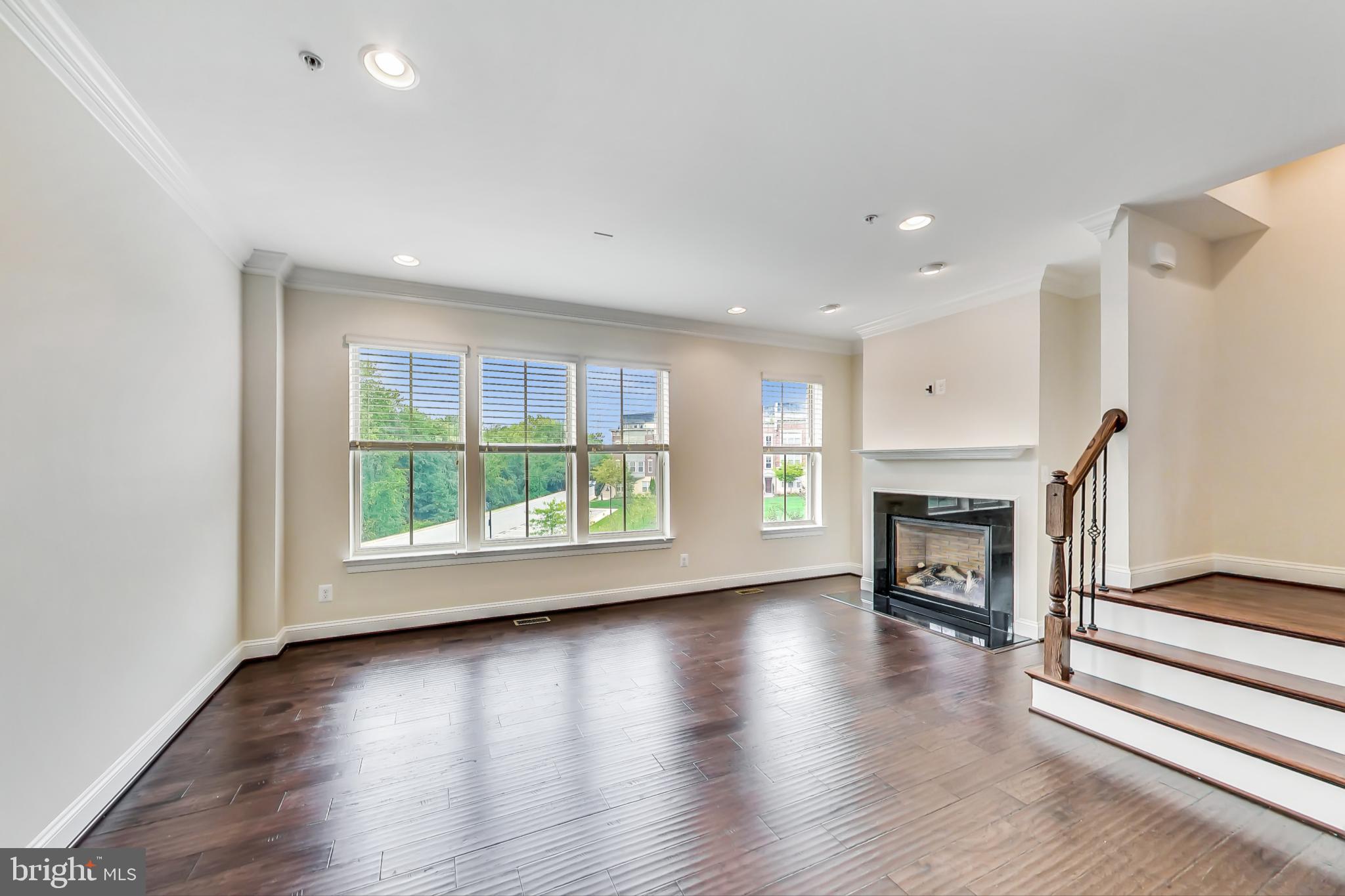 an empty room with wooden floor a fireplace and windows