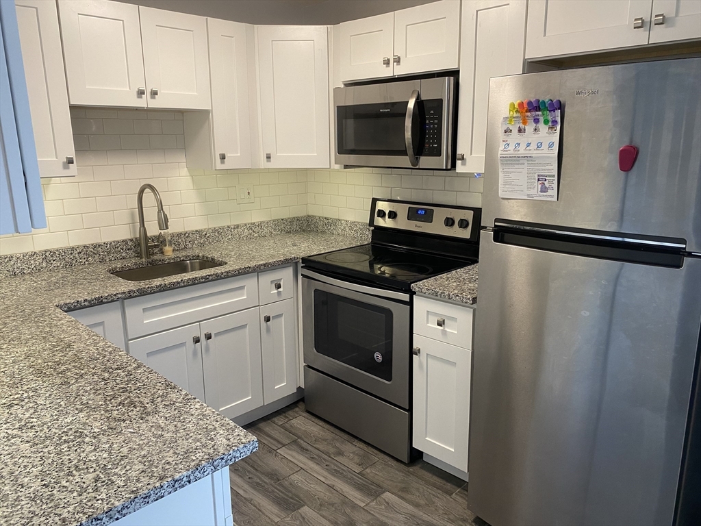 a kitchen with stainless steel appliances white cabinets and a stove top oven