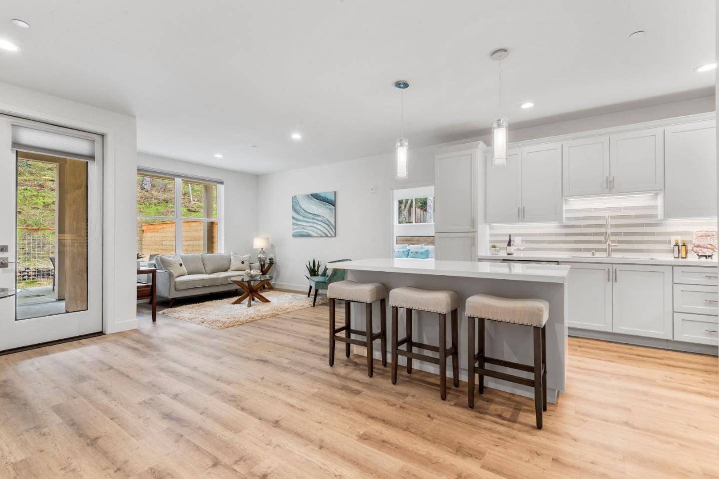 a living room with stainless steel appliances granite countertop furniture wooden floor and a kitchen view