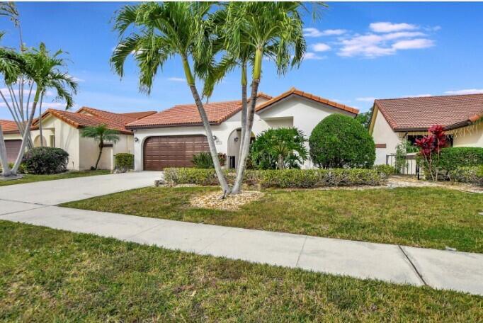 a front view of a house with a yard and palm trees