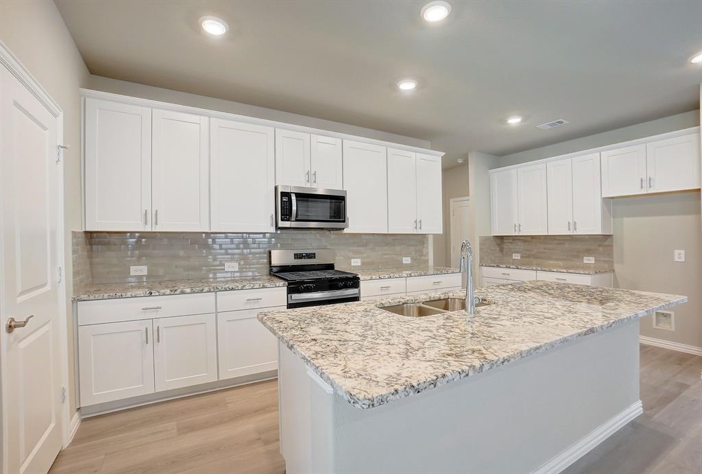 a kitchen with sink stove microwave and cabinets