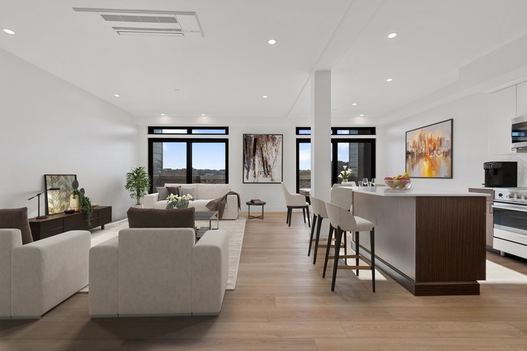 a living room with couches and kitchen view with wooden floor