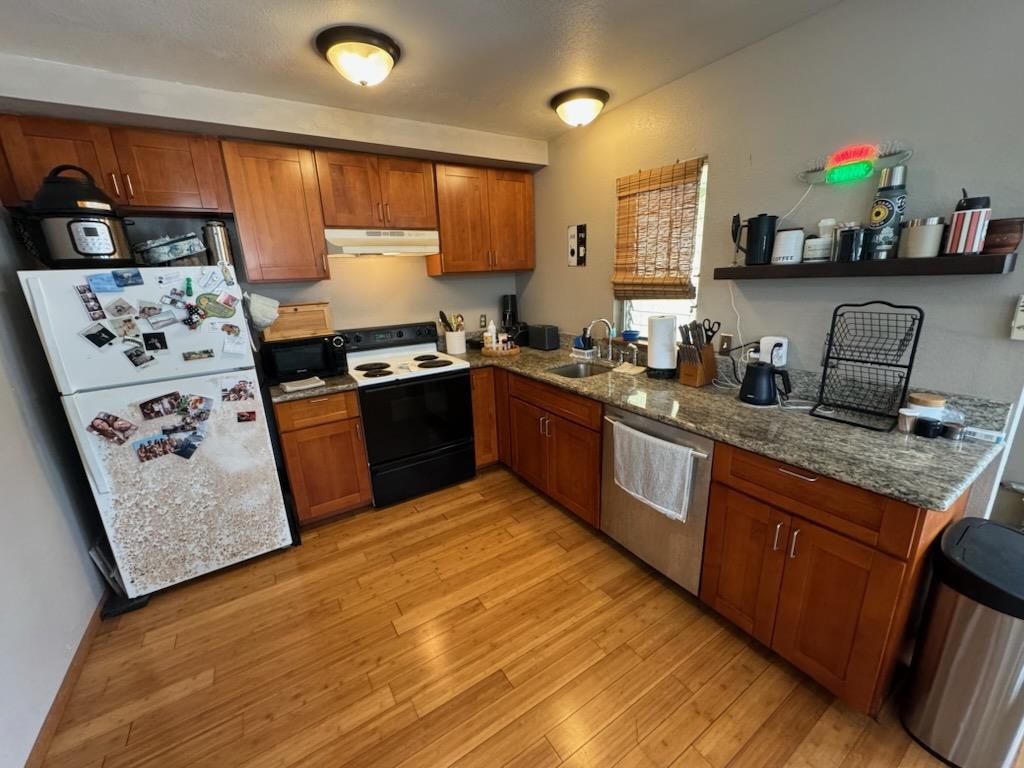 a kitchen with stainless steel appliances granite countertop a sink stove refrigerator and cabinets