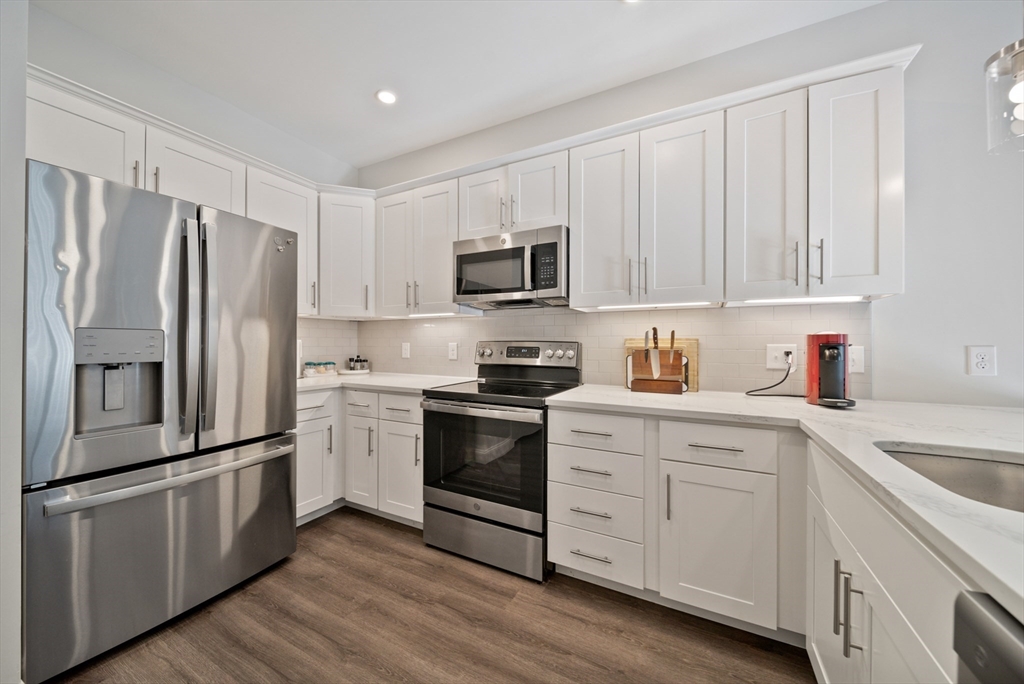 a kitchen with granite countertop white cabinets and stainless steel appliances