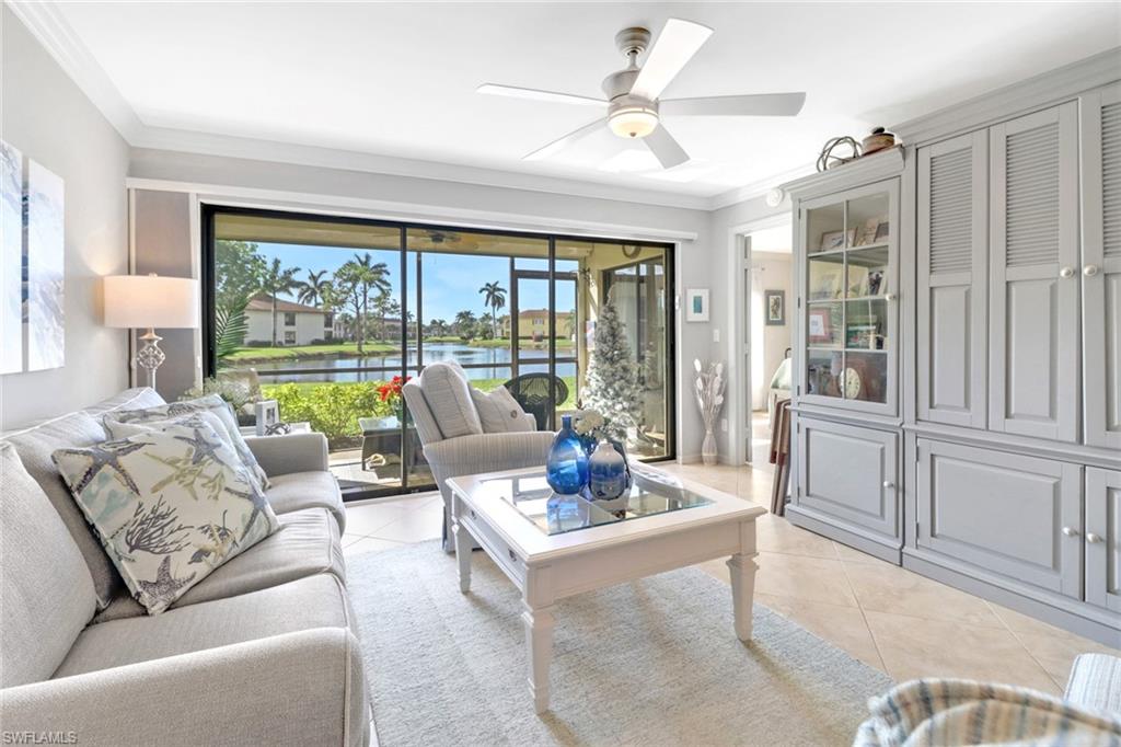 Living room featuring light tile patterned floors, a water view, ceiling fan, and a healthy amount of sunlight