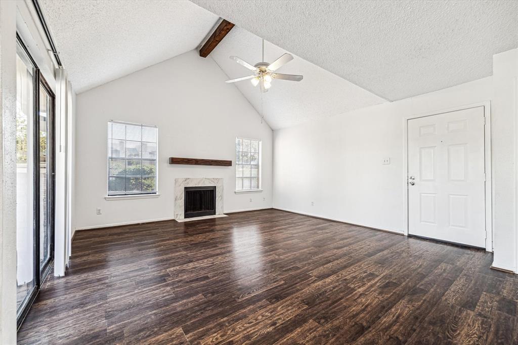 an empty room with wooden floor fireplace and windows